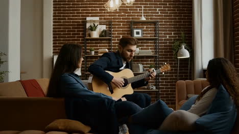 man plays acoustic guitar for friends in a cozy living room