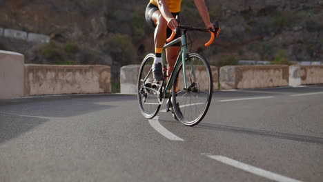 witness a male cyclist's climb up a mountain road in this tracking video. he's involved in cycling training on a sunny day along a hilly highway road