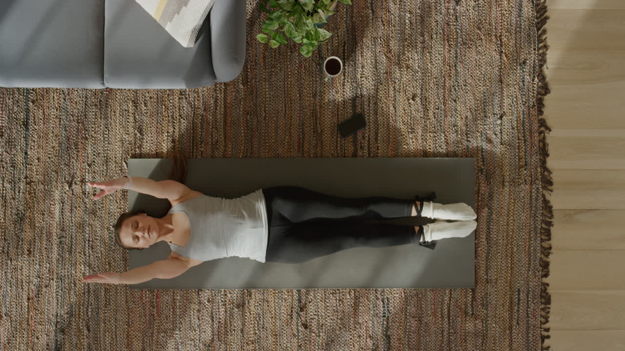 vista superior mujer de yoga ejercitando un estilo de vida saludable estirando el cuerpo flexible disfrutando del entrenamiento en casa practicando atención plena en la colchoneta de ejercicios