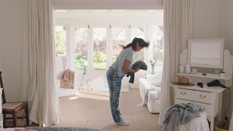 happy teenage girl dancing in bedroom to music enjoying weekend morning having fun celebrating carefree lifestyle wearing pajamas at home