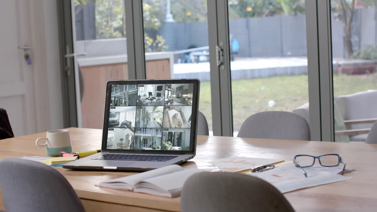 portátil en la mesa de comedor que muestra seis vistas de cámaras de seguridad domésticas, cámara lenta