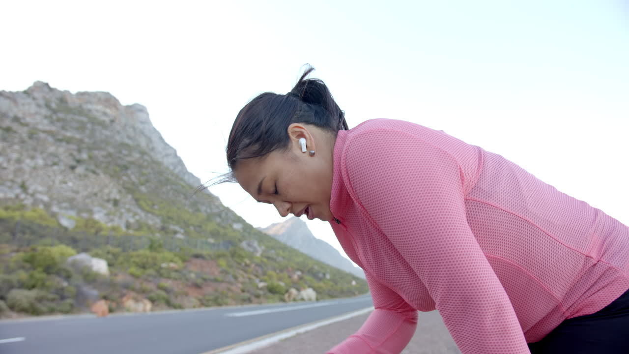 Exercising outdoors, woman in pink jacket taking break on mountain hike