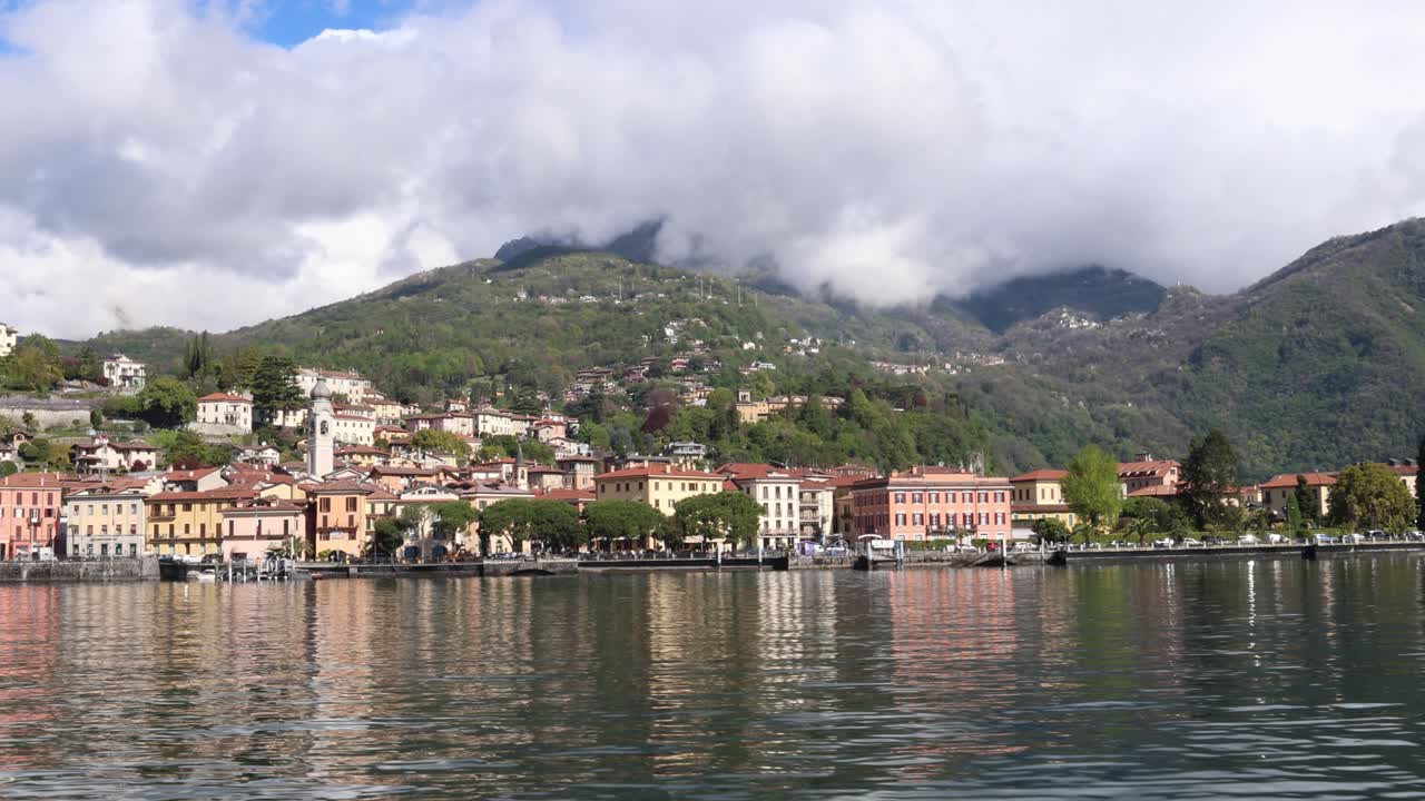 Crossing lake Como towards Italian coastal town with colorful houses, Menaggio