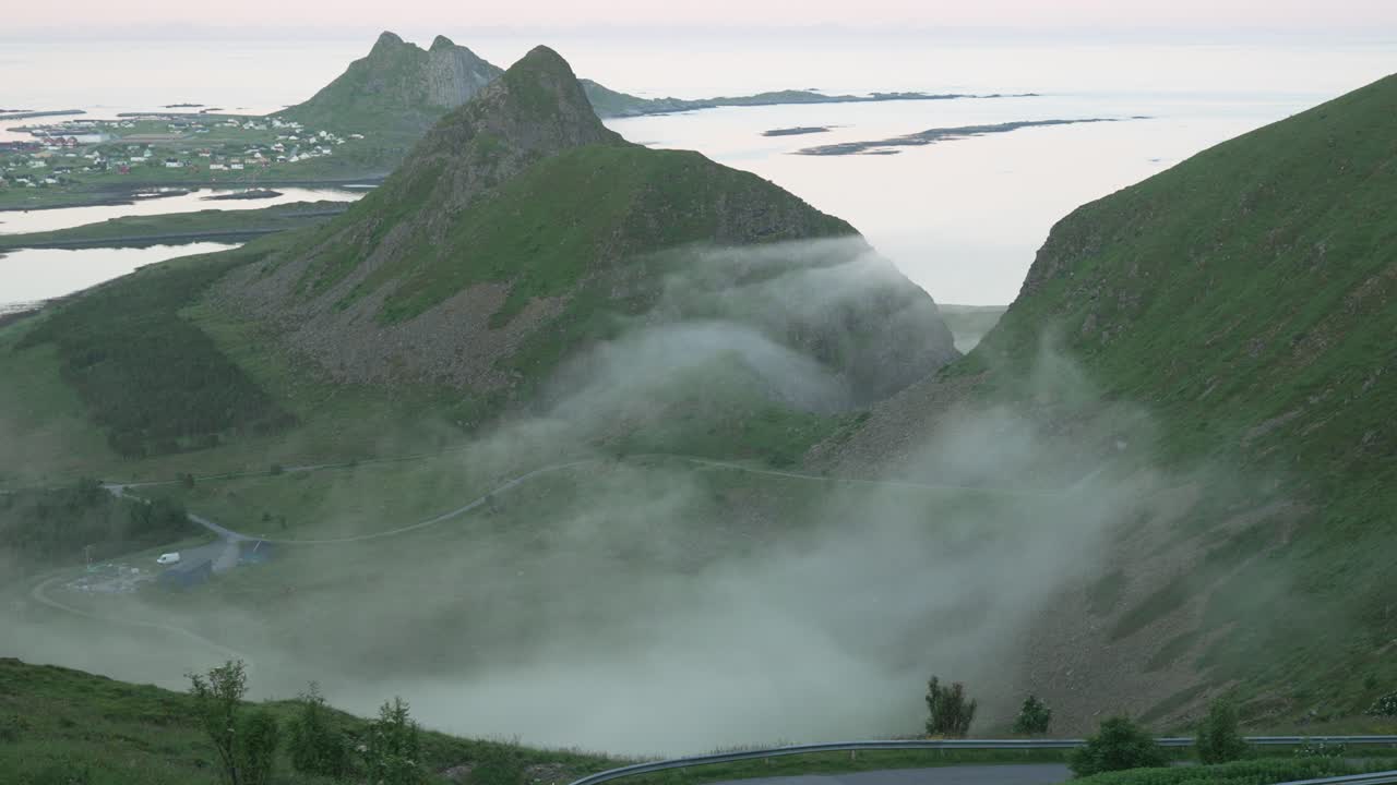 A mesmerizing view of Værøy Island as clouds slowly drift between the mountains, covering the valley below. Perfect for cinematic, nature, and atmospheric scenery footage