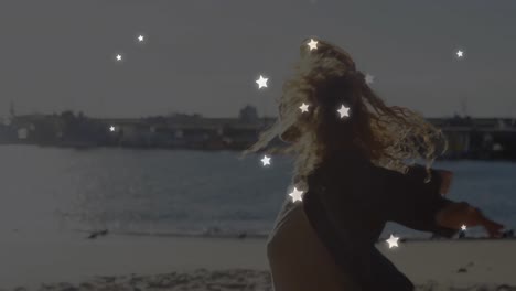 animation of stars over caucasian woman at beach