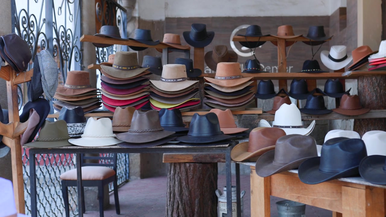Traditionelle Cowboyhüte auf einem Markt in Mexiko ausgestellt. – Schwenkaufnahme.