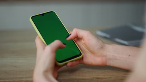 smartphone de pantalla verde con las manos cerca. niña navegando por el contenido de internet.