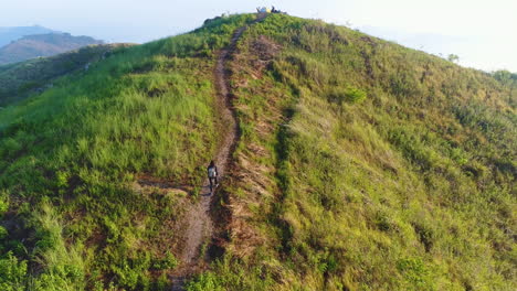 aerial orbit shot following a woman hiker on top of a mountain