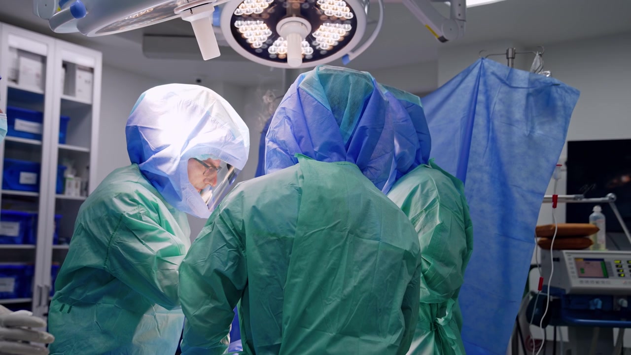 Equipe chirurgica che circonda il paziente durante l'operazione. Medici con caschi protettivi eseguono un intervento di chirurgia traumatologica