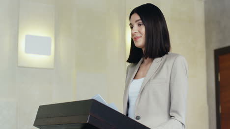 close-up view of caucasian businesswoman speaker on a podium wearing formal clothes and talking in a conference room