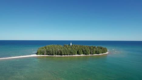 Drone-aerial-shot-of-a-small-island-with-light-house-overlooking-a-large-body-of-water