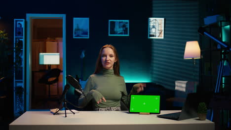un adolescente sonriente presentando a sus seguidores un modelo de tableta de pantalla verde