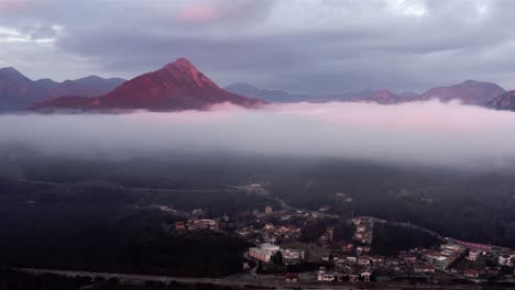 AERIAL---Low-clouds-above-mountain-village-at-Lake-Skadar,-Montenegro,-pan-left