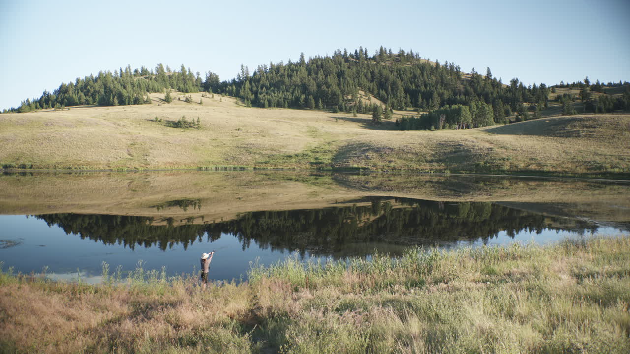 pescador lanza línea en estanque escénico con reflejo de montañas, canadá