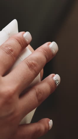 woman in white clothes with stylish manicure taps hand on knee sitting in room close view. young woman waiting for queue. lifestyle and beauty