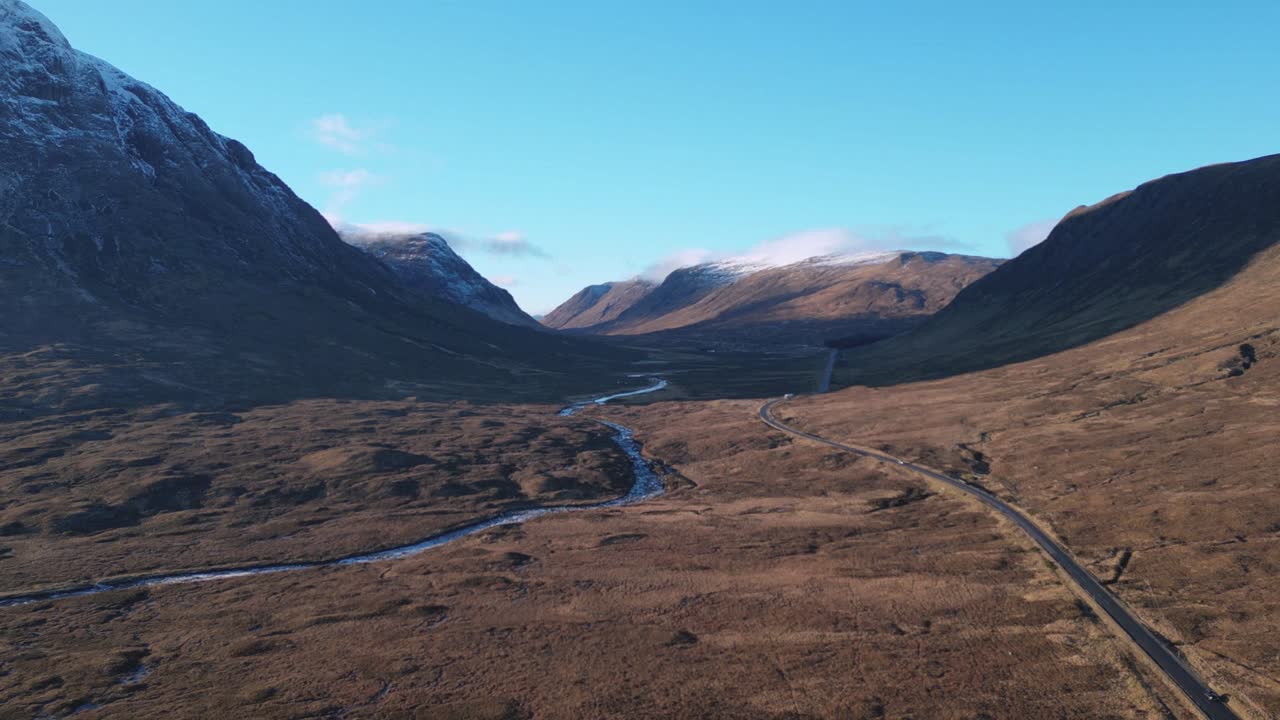 valle de glencoe con carretera y río sinuosos, tierras altas escocesas, paisaje sereno, vista aérea