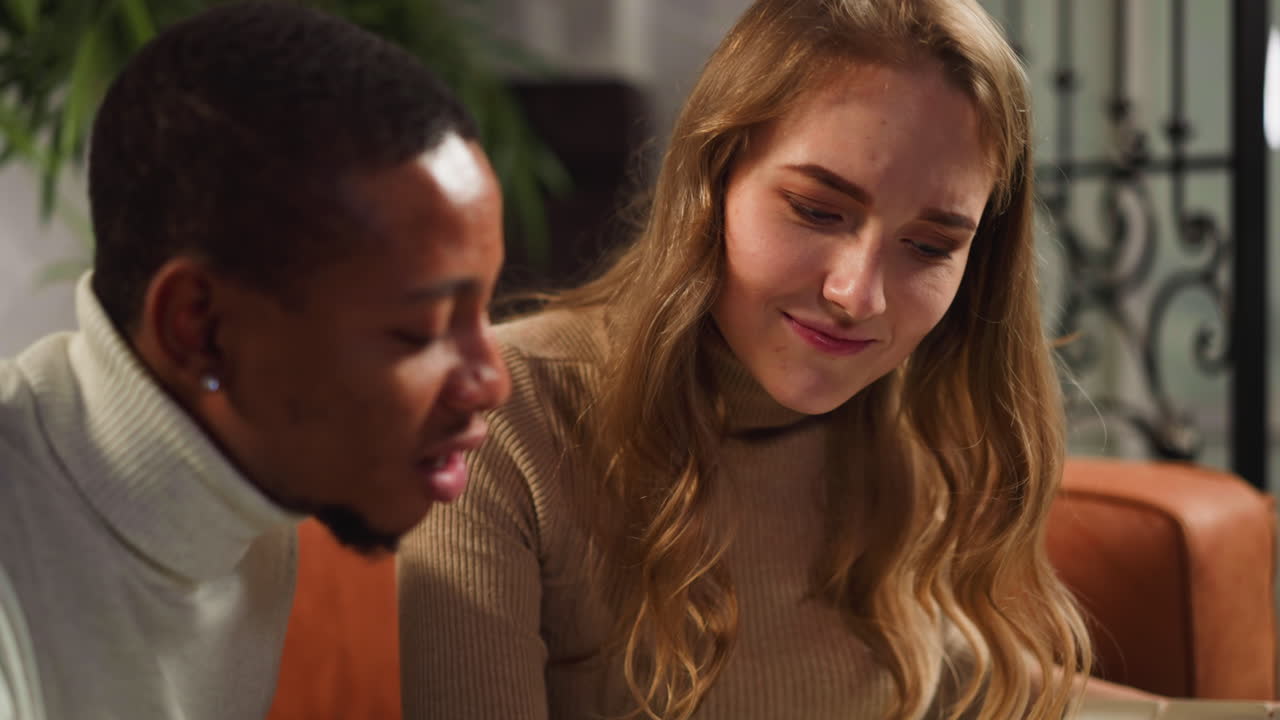 una mujer le pregunta a un colega negro sobre la familia mirando un libro de fotos