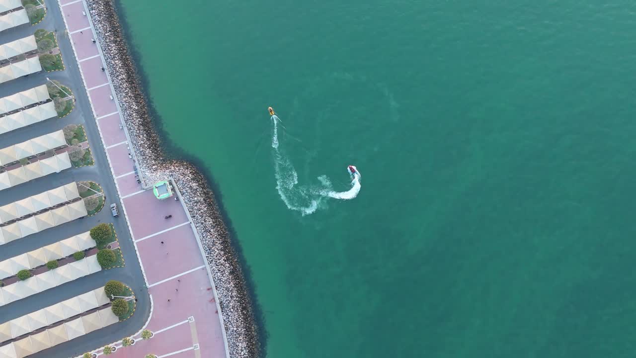 4K top-down aerial of a jet ski towing an inflatable tube near Kuwait’s coast. Stunning turquoise water, waterfront geometry, and thrilling water sports action make this clip highly versatile.