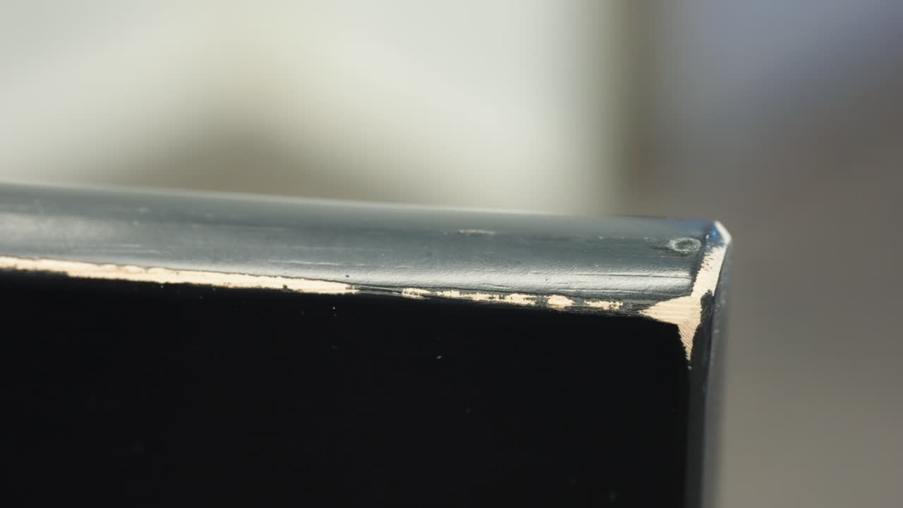 Camera pans along worn corner, paint dents and scrapes revealing bare timber