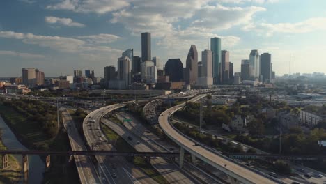 aerial view of cars on freeway with downtown houston in the background