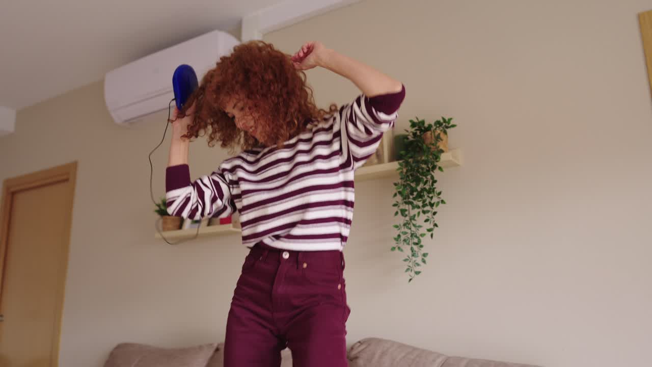 Donna che balla felice nel suo salotto con un lettore musicale