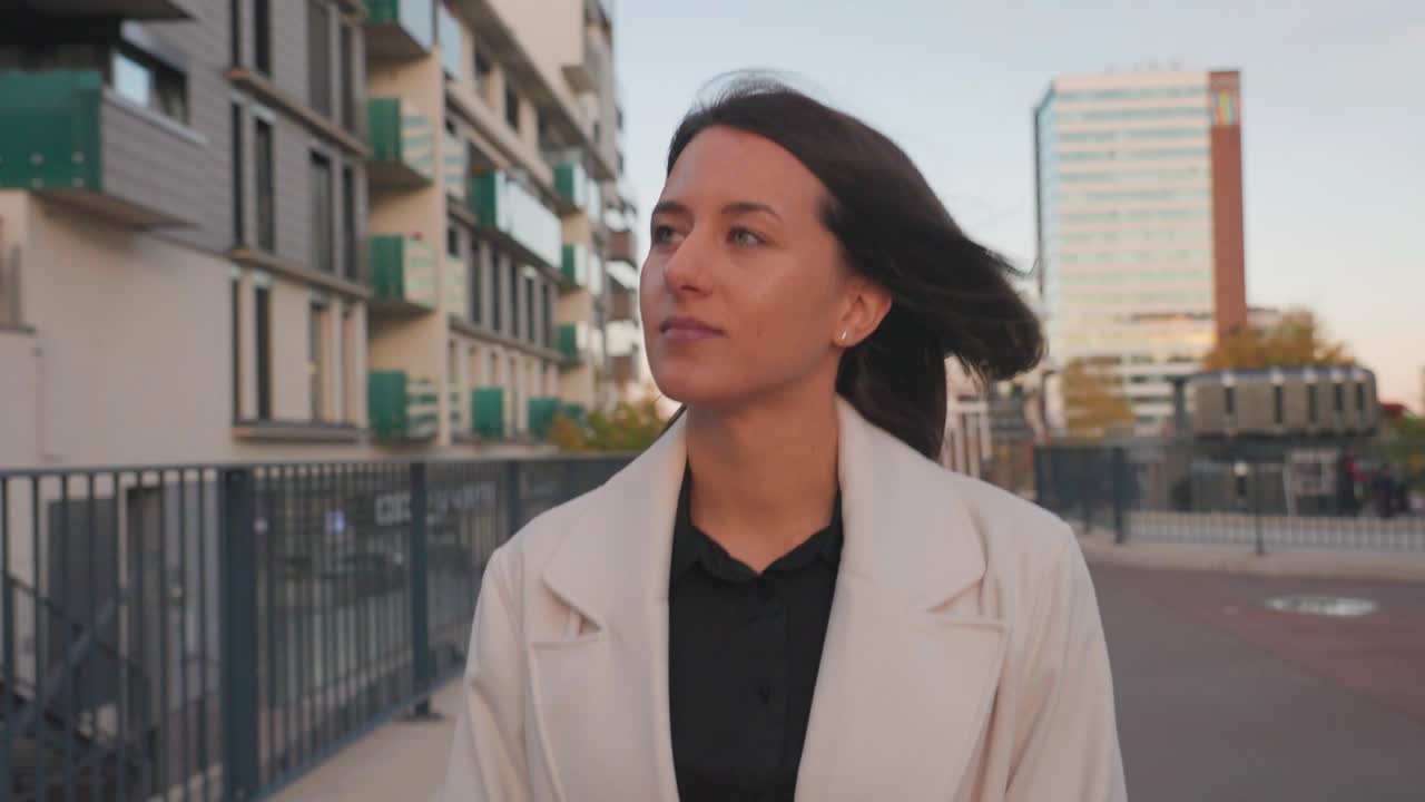 atractiva morena camina por la calle de la ciudad cerca de un edificio de varios pisos y disfrutar de la vista