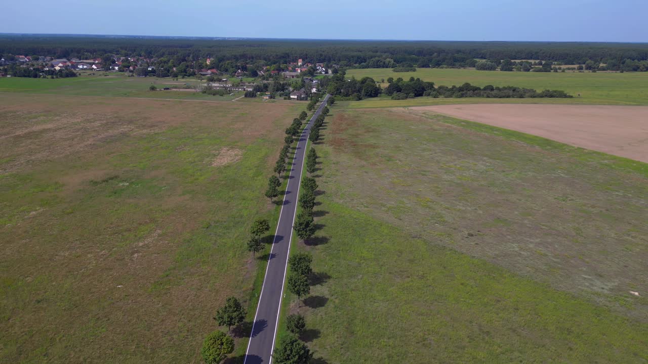 carretera de asfalto vacía que cruza un paisaje rural con árboles y campos. espectacular vista aérea vuelo volar drone inverso