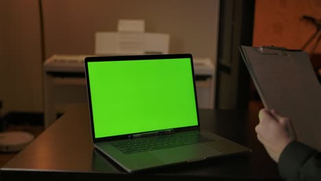 escribir notas científicas detrás de una computadora portátil de pantalla verde en casa