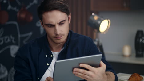 serious businessman reading bad news on tablet computer at home office.