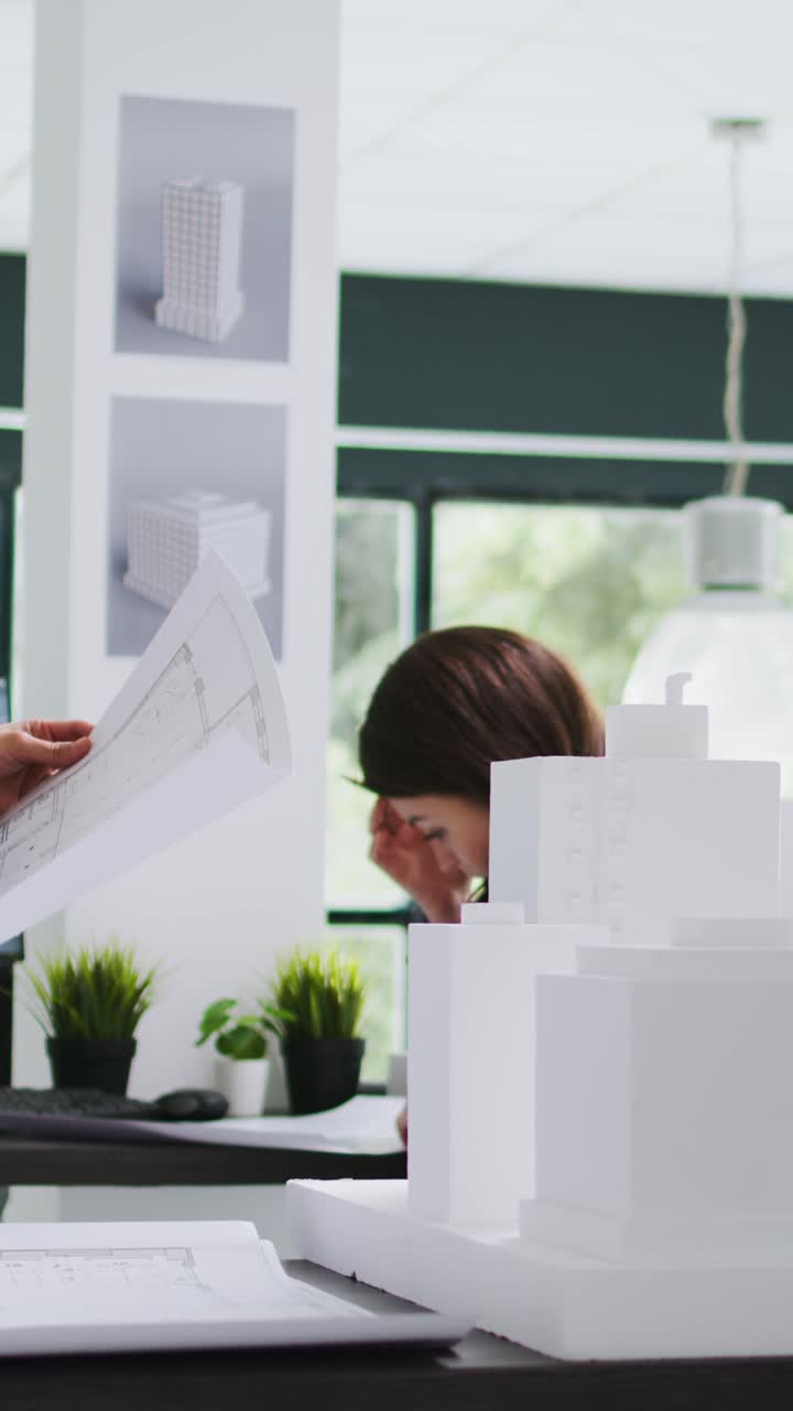 Vídeo vertical: Arquitecto de oficina mirando maqueta de edificio