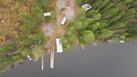 overhead of campervan in fir forest near lakeshore and wooden pier in sweden