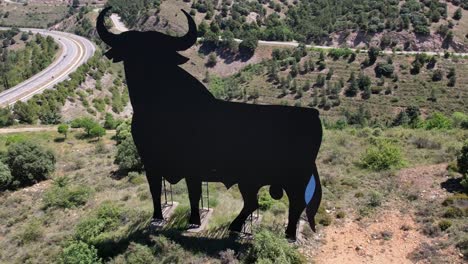 Vuelo-En-Círculo-De-Vista-Aérea-Alrededor-Del-Símbolo-De-Span-El-Toro-De-Osborne,-Un-Enorme-Toro-De-Metal-Negro-En-La-Cima-De-Una-Colina