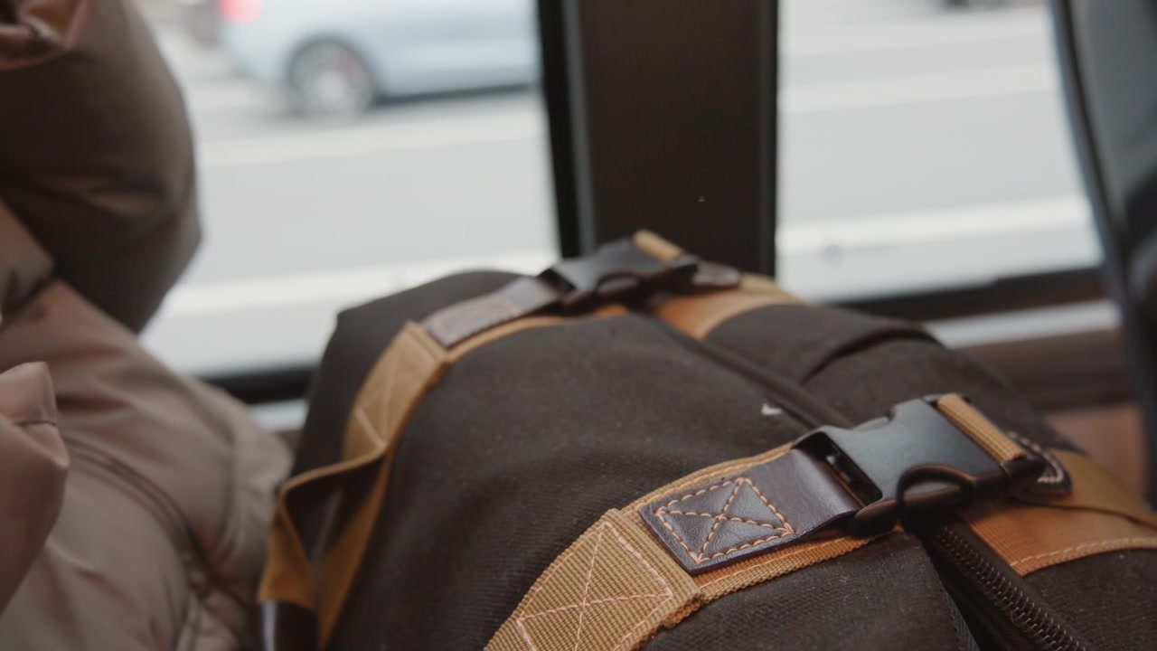 Mujer asegura su bolso. Dama ajustando cuidadosamente la hebilla de su mochila mientras viaja en el concurrido transporte público de la ciudad. Pasajera asegura diligentemente su mochila durante la hora pico en un autobús urbano abarrotado.