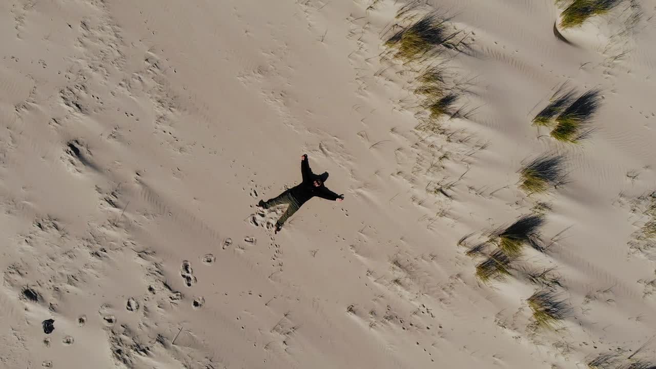Aerial, top down, drone shot of a man laying on a beach, sunny day, on Langeoog island, at the Nordsee, in North Germany