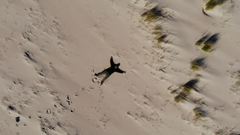 aerial, top down, drone shot of a man laying on a beach, sunny day, on langeoog island, at the nordsee, in north germany
