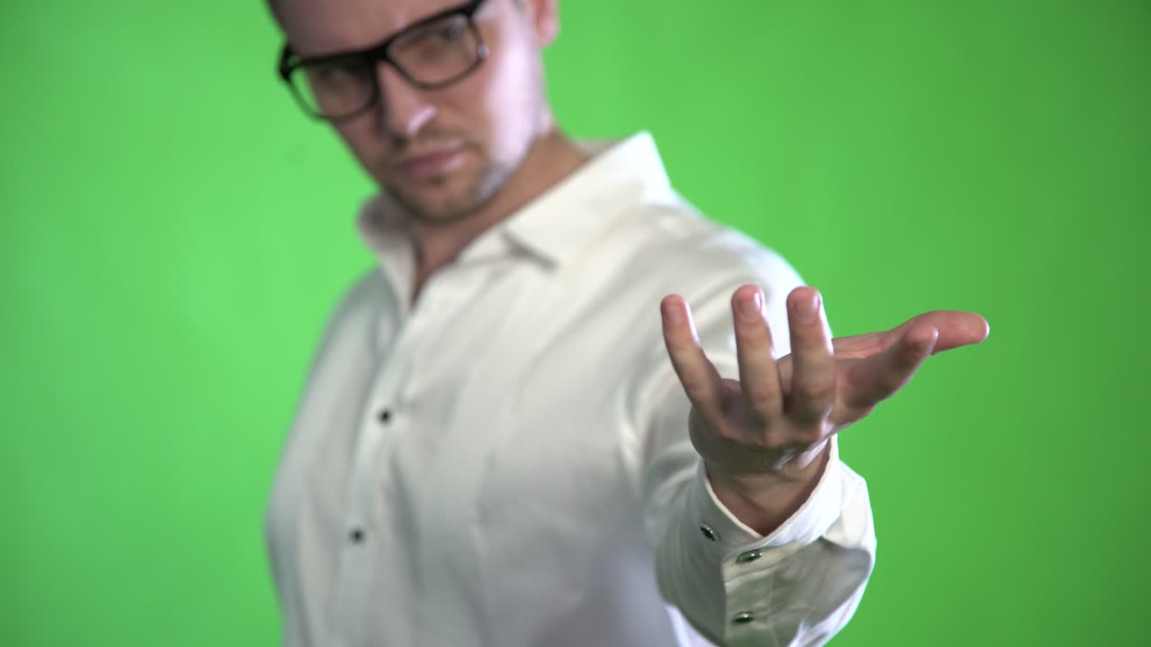 un hombre texturizado con cerdas y gafas controla sus manos con un holograma en un fondo verde