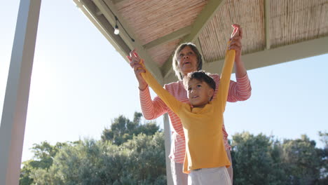 abuela y nieto bi-raciales felices haciendo yoga, meditando en la terraza, cámara lenta