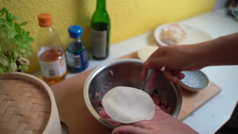 Male-hands-preparing-Japanese-Gyoza-Dumplings-in-bright-kitchen-setting-with-spoon,-locked-off-view