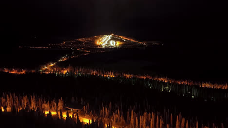 Aerial-view-tilting-over-cabins-and-streets,-toward-the-slopes-of-Iso-Syote,-Finland