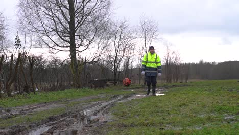 man wear yellow reflective safety jacket and walk toward near muddy road