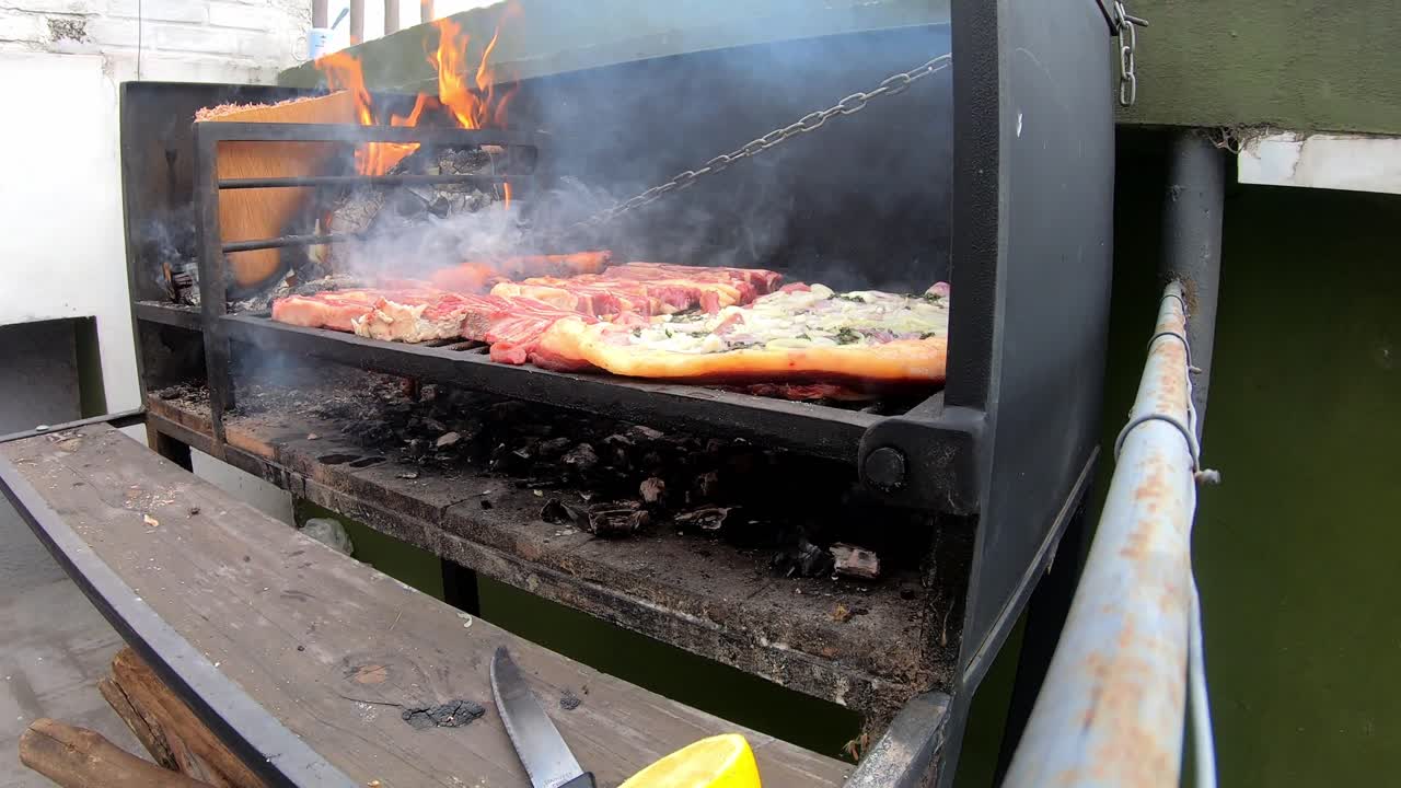 Lapso de tempo de um homem preparando um assado com carvão em um dia ensolarado em uma churrasqueira preta.