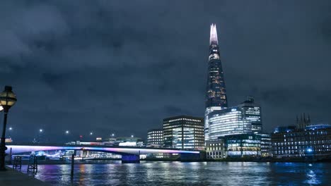 Night-time-lapse-of-traffic-on-London-Bridge-at-nighttime,-over-the-river-Thames-and-with-the-illuminated-Shard-building-in-the-background