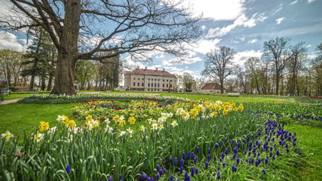 european home and people walking on path on beautiful day with bright flowers blooming