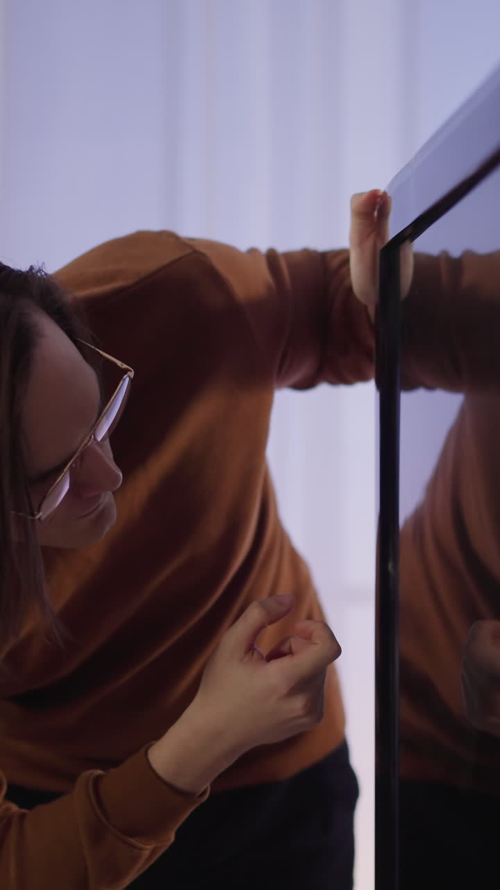 hombre de cabello largo toca el dedo en la pantalla de la televisión inteligente de pie junto a la ventana en casa en cámara lenta. hombre trata de arreglar el equipo de televisión. dispositivo doméstico roto