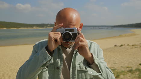 man taking pictures with camera on beach