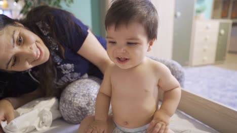 una madre sonriente mirando a su bebé.