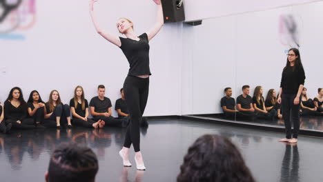 female ballet student at performing arts school performs for class and teacher in dance studio