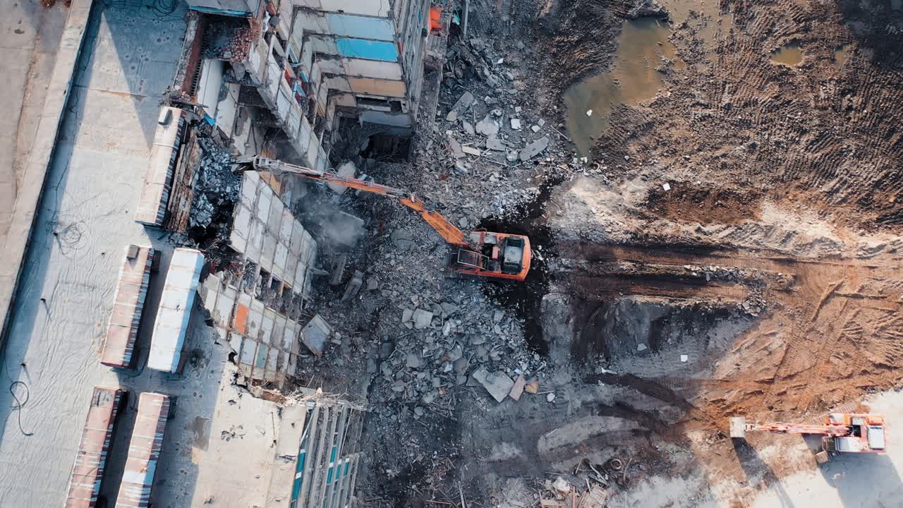 Tractor with a special bucket dismantles a collapsed building after a disaster. Construction work in the city. Shooting from the air
