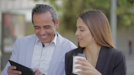 colegas felices usando tableta digital al aire libre
