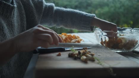 female hands cleaning golden chanterelle mushrooms on wooden board outside